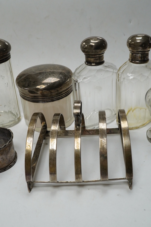 An Art Deco silver five bar toast rack by Charles S. Green & Co Ltd, Birmingham, 1935, 9cm, a silver napkin ring and six assorted silver topped glass toilet bottles. Condition - poor to fair